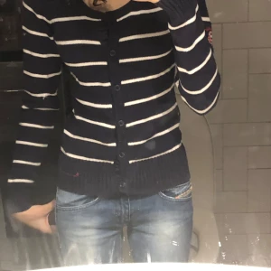 Marinblå och vit randig kofta från Bondelid - Säljer en snygg marinblå kofta från Bondelid med vita ränder. Koftan har långa ärmar och knappar framtill. Perfekt för en stilren look. 🧥