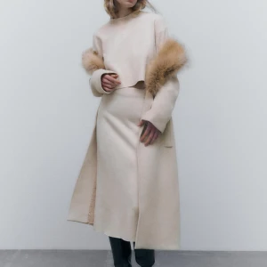 Zara-Beige set med lång kjol och croppad tröja - Elegant beige set bestående av en lång kjol och en croppad tröja. Tröjan har långa ärmar och en enkel design, medan kjolen är figurnära och stilren. Perfekt för en minimalistisk look. Tröjan är i st s men är liten i st och kjolen är i st s.