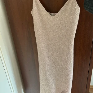 Glittrig champagnefärgad klänning  - Snygg glittrig klänning i champagnefärg från NLY One. Den har en tight passform och en skulpterande butt scrunch baktill. Perfekt för en festlig kväll!💕Säljer då den inte kommit till användning 