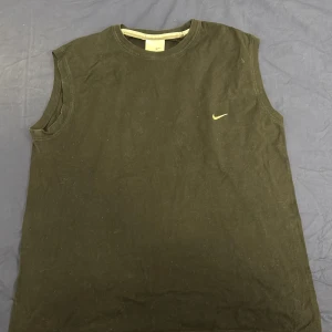 Svart ärmlös topp från Nike - Säljer en svart ärmlös topp från Nike. Perfekt för träning eller en avslappnad dag. Den har en enkel design med en liten Nike-logga på bröstet. Tillverkad i Turkiet.