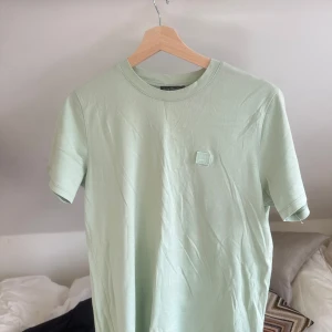 Acne t-shirt - Snygg ljusgrön t-shirt med en diskret logga på bröstet. Perfekt för en avslappnad stil. Tillverkad i mjukt material för extra komfort.
