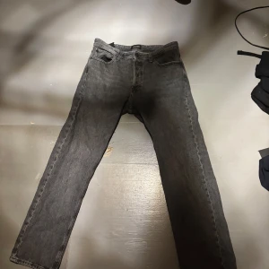 Grå jeans från Jack & Jones - Snygga grå jeans från Jack & Jones med klassisk femficksdesign. De har en straight passform och är perfekta för en avslappnad stil. Tillverkade i slitstarkt denim som ger en cool look. Nypris 599kr