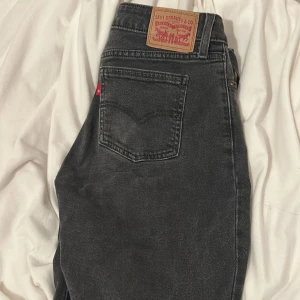 Svarta jeans från Levi's - Snygga svarta low waist bootcut jeans från Levi's med klassisk femficksdesign och knappgylf.