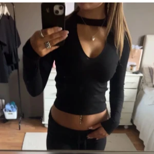 Svart långärmad topp med choker-detalj - Snygg svart långärmad topp med en unik choker-detalj och djup v-ringning. Perfekt för en trendig look. Säljer pgv att den inte använd så mcyket längre❤️