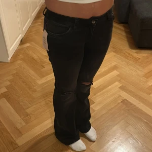 Svarta bootcut jeans från Nelly - Snygga svarta bootcut jeans från Nelly med slitna detaljer på knäna. Säljer då det aldrig kommit till användning. 