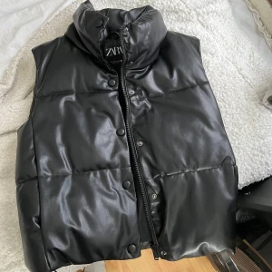 Svart fejk skinn väst  - Säljer min svarat fejk skinn väst från Zara då den bara hänger i garderoben nu mera. Den är i bra skick och super fin nu till våren. Det är storlek xs men skulle säga att den passar s också. 