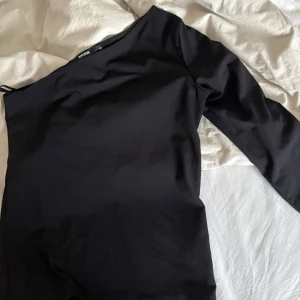 Svart oneshoulder topp  - Snygg svart oneshoulder topp. Perfekt för en stilren men festlig look 