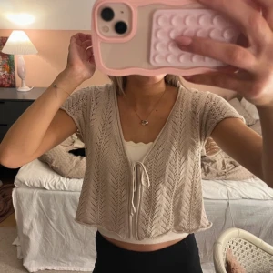 Beige stickad bolerotopp - Säljer supersöt beige stickad bolerotopp med korta ärmar och knytband framtill!🌸🌸🥰