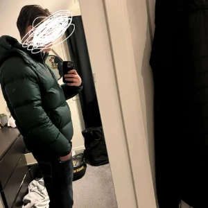 Mörk grön Ralph lauren jacka med dragkedja - Säljer en snygg grön pufferjacka med dragkedja. Jackan har en hög krage och långa ärmar, perfekt för kyligare dagar. Den är stilren och passar bra till jeans eller andra casual outfits.
