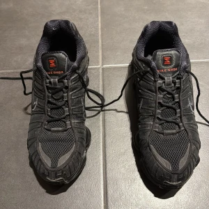 Svarta Nike Shox sneakers - Säljer ett par svarta Nike Shox sneakers med unik fjädrande sula och snörning. Skorna har en sportig design med diskreta detaljer och Nike-logga på sidan. Perfekta för en aktiv livsstil.