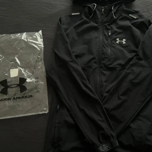  Under Armour jacka - Säljer en Under Armour jacka för halva priset. Passa på. Jackan har en diskret logga på bröstet och reflekterande detaljer på axlarna. Perfekt för träning eller en aktiv vardag. Nypris 1200 kr.