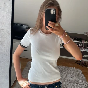 Vit t-shirt från Zara med glittriga ärmslut - Säljer en stilren vit t-shirt från Zara med korta ärmar och glittriga svarta/guldiga ärmslut. Den är köpt för ungefär 1 år sedan men den har aldrig används. Skriv om ni vill ha fler detaljer eller bilder🥰
