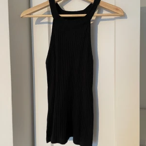 Svart ribbad linnetopp från Even&Odd - Säljer en stilren svart ribbad linnetopp från Even&Odd. Toppen har breda axelband och en enkel design som passar perfekt till olika outfits.