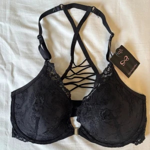 Svart spets-bh med snörning  - Jättesnygg svart bh från Hunkemöller med spetsdetaljer framtill och dekorativ snörning i ryggen. Med justerbara axelband och öppning där fram. Helt ny med prislapp kvar, säljer pga köpte fel storlek. Nypris 379🩷