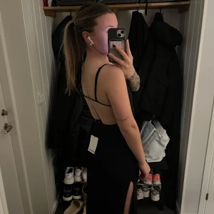 Svart långklänning med slits - Säljer en elegant svart långklänning med smala axelband och har slits på båda sidorna! Så fin öppen rygg! Klänningen är helt ny med prislappen kvar!  Den passade inte som jag velat och tog för lång tid på mig så är för sent att skicka tillbaka 