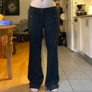 Svarta byxor med knappar - Säljer dessa svarta byxor i ett lite tjockare material. De har spännen på båda sidor så man kan justera midjestorleken. Midja: 84-94 cm. Innerbenslängd: 80 cm. Ytterbenslängd: 105 cm. Jag är 170!