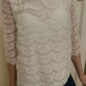 Vit spetsblus med trekvartsärm - Säljer en superfin vit spetsblus med trekvartsärm. Perfekt för både vardag och fest! Blusen har ett vackert mönster och är i mycket bra skick. Passar perfekt till jeans eller kjol för en chic look.