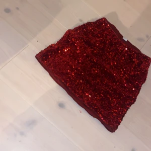 Röd glittrig kjol - Säljer en superfin röd glittrig kjol perfekt för festliga tillfällen. Den är täckt med paljetter som verkligen. perfekt för jul. Änvänd 1 gång så praktiskt sätt ny ❤️
