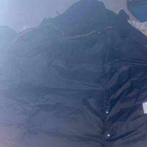 Svart jacka från Hollies - Säljer en svart jacka från Hollies i storlek 34. Den har en stilren design med knappar och är perfekt för kyligare väder. Jackan är i bra skick och har en snygg orange detalj längs sömmarna. Perfekt för höst och vinter! Skulle vill ja byta mot en 32