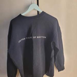 Säljer en snygg mörkblå sweatshirt från United Colors of Benetton. Den har en klassisk design med logotypen tryckt på framsidan. Perfekt för en avslappnad stil och passar till alla tillfällen. Tröjan är i bra skick och redo för en ny ägare!