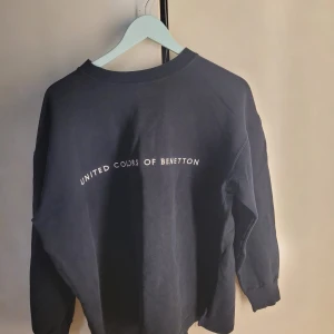 Mörkblå sweatshirt från United Colors of Benetton - Säljer en snygg mörkblå sweatshirt från United Colors of Benetton. Den har en klassisk design med logotypen tryckt på framsidan. Perfekt för en avslappnad stil och passar till alla tillfällen. Tröjan är i bra skick och redo för en ny ägare!