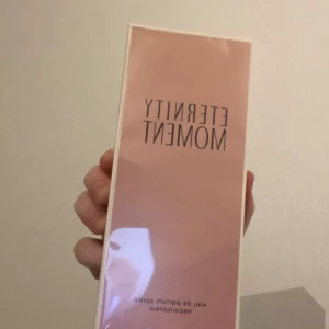 Eternity Moment Eau de Parfum från Calvin Klein - Säljer en elegant och fräsch Eternity Moment Eau de Parfum från Calvin Klein. Flaskan är stilren och rektangulär med en ljusrosa ton, perfekt för den som älskar en romantisk och blommig doft. Kommer i en matchande ljusrosa kartong. Perfekt present eller för att unna dig själv! 🌸