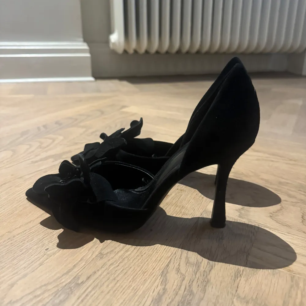 Säljer ett par eleganta svarta pumps i mycket bra skick. De har en spetsig tå och en vacker blommig detalj framtill som ger en extra touch.Perfekta för festliga tillfällen eller en utekväll. Klacken är hög och ger en snygg siluett. Väldigt fint skick andvända 2 ggr!  Storlek 37 men lite stora i storleken! . Skor.