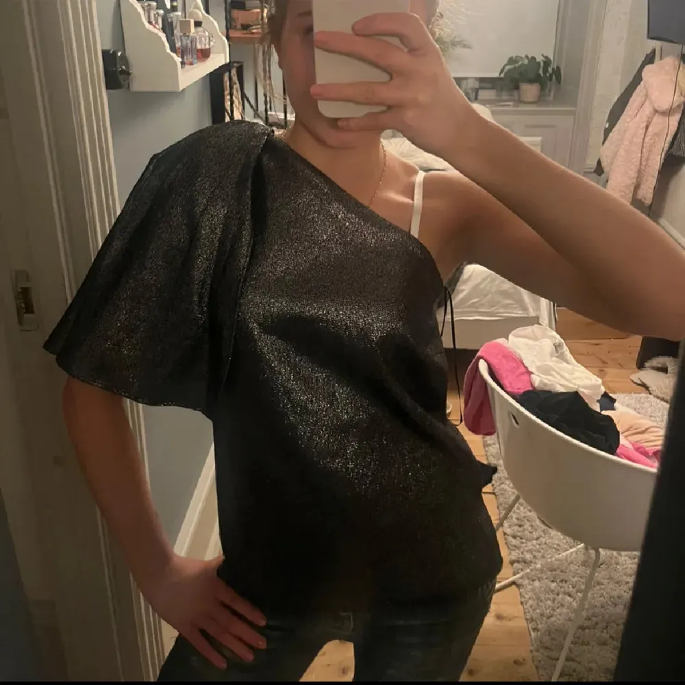 Funderar på att sälja min sjukt snygga och unika glittriga fest topp❣️PERFEKT till nyår!! svart glittrig  oneshoulder topp med volang. Såå snygg, endast använd en gång väldigt fint skick, strl S, jag är ca 165 cm på bild. Toppar.