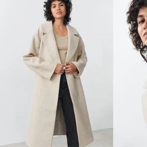 Beige kappa med bälte - Säljer en beige kappa i perfekt skick, endast använd en gång. Passar till nästan alla outfits. Storlek XS, men modellen är något rymlig. Jag tycker kappan är otroligt snygg, men tyvärr är den lite för stor för mig.