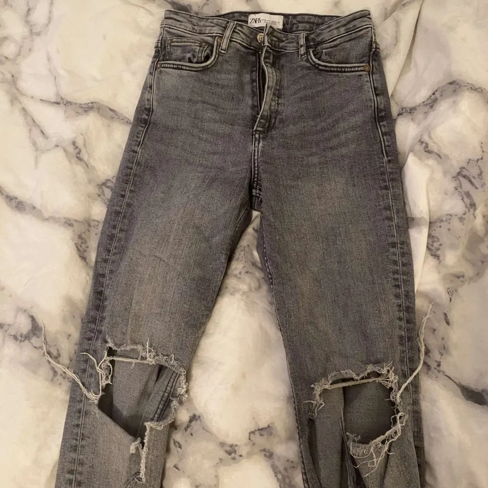 Säljer ett par grå bootcut jeans från Zara i storlek 36. De finns fickor fram, bak och hål på knäna. Skulle säga att de är i bra skick och har inga hål eller så utom att det finns små blekningsfläckar på höger bakben som syns på sista bilden. 💗. Jeans & Byxor.