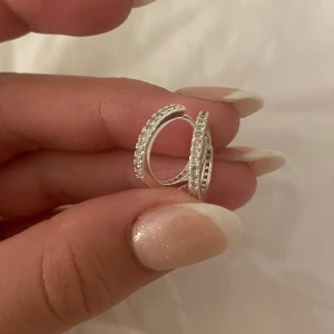 Silverfärgade örhängen med stenar - Snygga och eleganta silverfärgade örhängen med glittrande stenar. Perfekta för att ge en touch av glamour till vilken outfit som helst. De är i mycket bra skick och passar både till vardags och fest. Enkla att matcha med andra smycken.