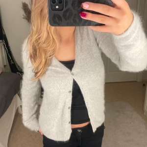 Grå kofta från Twilfit - Mysig och stilren grå kofta från Twilfit i storlek S. Perfekt för kyliga dagar med sin mjuka och bekväma passform. Koftan har knappar framtill och långa ärmar, vilket gör den idealisk för både vardag och lite finare tillfällen. Ett måste i garderoben för höst och vinter! 🍂