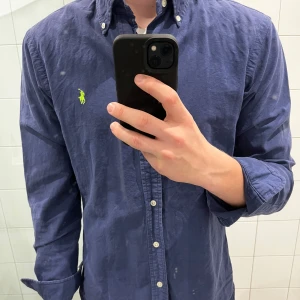 Blå skjorta från Ralph Lauren - Säljer en snygg blå skjorta från Ralph Lauren i bra skick. Den har långa ärmar och en klassisk krage med knappar (pyttelitet hål i ena ändan på armen, bifogar bild). Perfekt för både vardag och fest! 💙