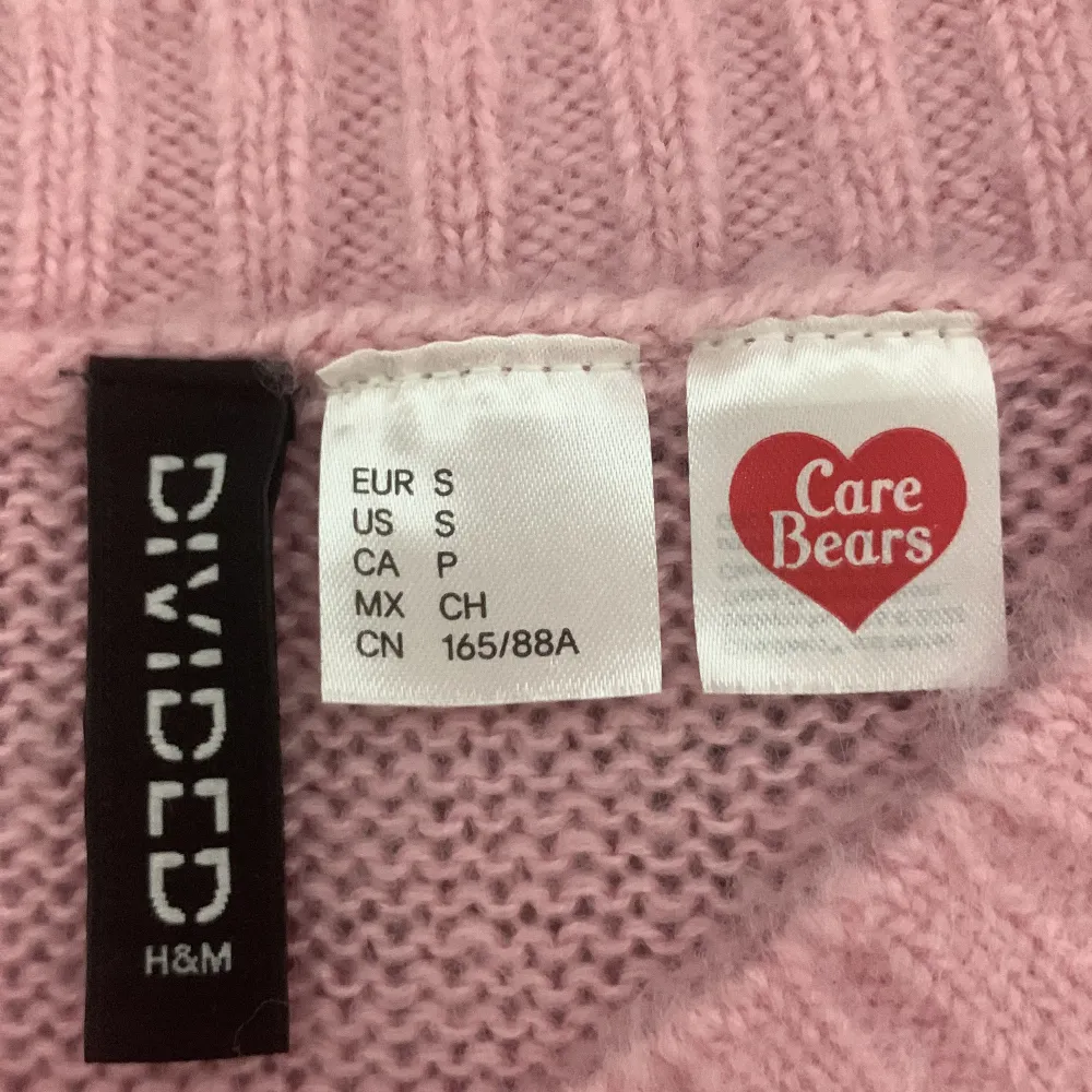 Supergullig rosa stickad tröja från H&M Divided med ett stort Care Bears-motiv på framsidan. Tröjan är croppad och har långa ärmar, perfekt för en mysig dag. Den är i bra skick och passar perfekt till jeans eller kjol. 🐻💖(kan bara mötas upp). Tröjor & Koftor.