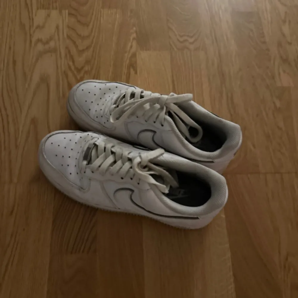 Säljer ett par klassiska vita Nike Air Force sneakers i bra skick. De har en stilren design med snörning och den ikoniska Nike-loggan på sidan. Perfekta för vardagsbruk och passar till nästan alla outfits. Lite slitna men fortfarande snygga och bekväma.. Skor.