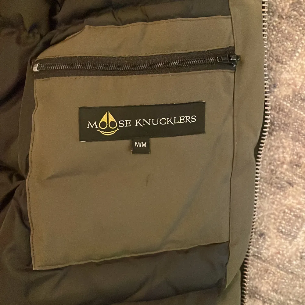 Säljer en olivgrön dunjacka från Moose Knuckles i mycket bra skick. Jackan har en fluffig pälsfodrad huva och stängs med dragkedja och knappar. Perfekt för kalla vinterdagar! 🧥❄️. Takit.