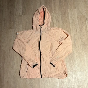 Beige rosa  vindjacka med huva - Säljer en beige rosa vindjacka med huva och dragkedja. Perfekt för vår och höst, med långa ärmar och en lätt, bekväm passform. Jackan är i bra skick och passar perfekt för vardagsbruk eller lättare utomhusaktiviteter.