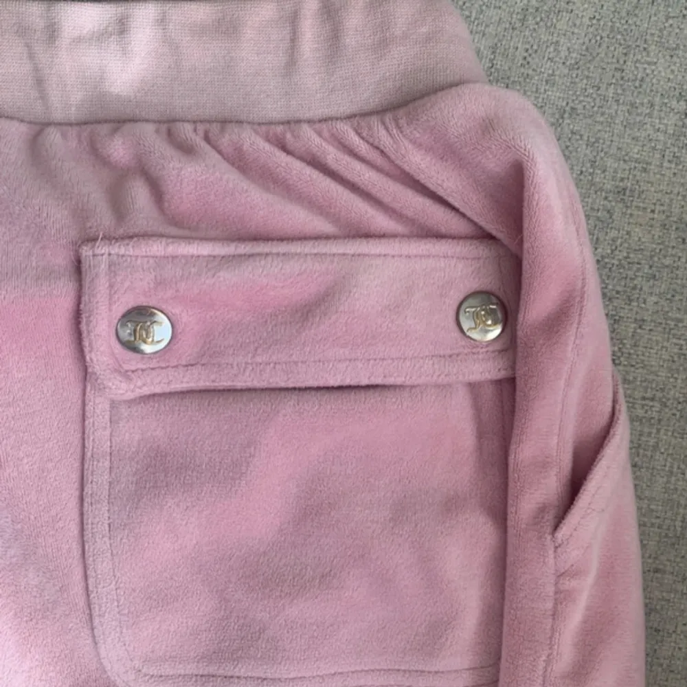 Supermysiga rosa mjukisbyxor från Juicy Couture i storlek 14/15. De är gjorda i ett mjukt material och har en elastisk midja för extra komfort. Byxorna har en snygg broderad logga och fickor med knappar. Perfekta för en chill dag hemma eller en avslappnad utflykt! 💖. Jeans & Byxor.