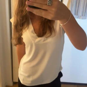 Vit v-ringad topp - Säljer en stilren vit v-ringad topp. Perfekt för både vardag och fest. Toppen har korta armar. Använd fåtal gånger. Kontakta mig vid frågor❣️