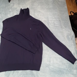 Mörkblå polotröja från Ralph Lauren - Säljer en snygg mörkblå polotröja från Ralph Lauren i tvättbar merinoull. Tröjan har en klassisk design med lång ärm och den ikoniska loggan broderad på bröstet. Perfekt för kyliga dagar och ger en stilren look. Perfekt för höst, vinter och vår. Passar både till vardags och lite finare tillfällen. Jättebra skick! Pris går att diskuteras!