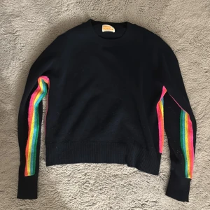 Svart tröja med regnbågsdetaljer från From Future - Säljer en snygg mörkblå tröja från From Future med coola regnbågsfärgade ränder längs ärmarna. Perfekt för att liva upp garderoben! Tröjan är i mycket  bra skick och har en normal passform. Den är långärmad och gjord i ett mjukt material som känns skönt mot huden. 100% Kashmir 
