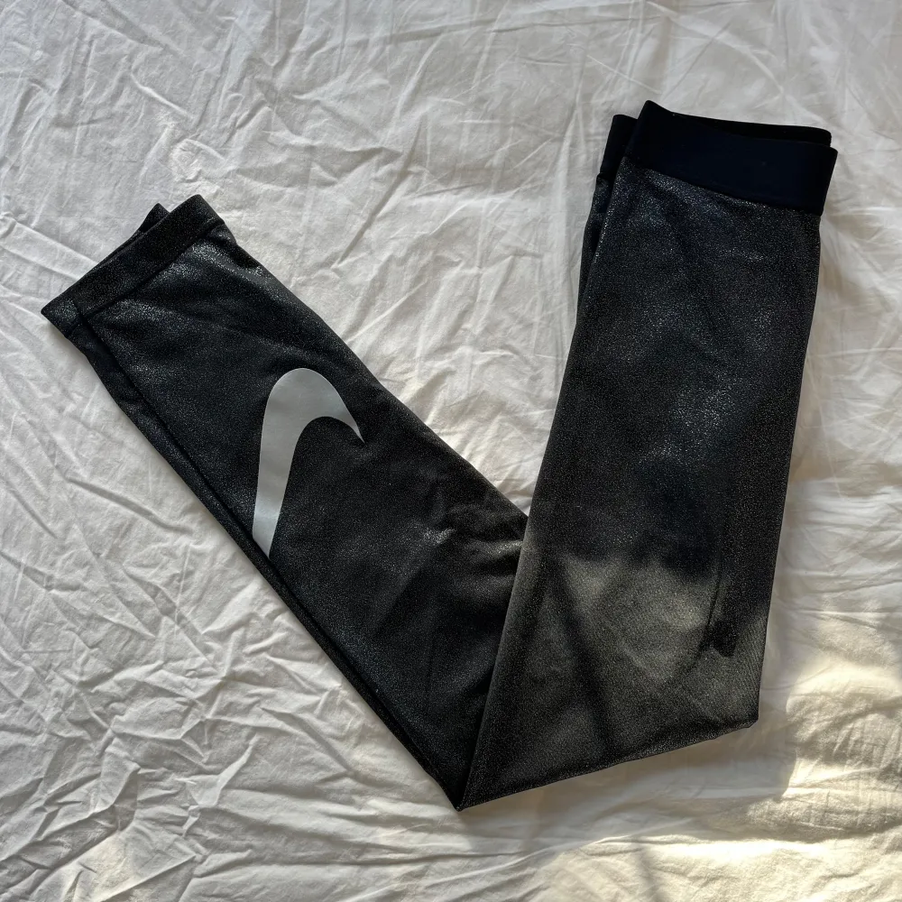 Snygga svarta leggings från Nike med en glittrig finish och det klassiska swoosh-loggan i vitt på benet!. Sportswear.