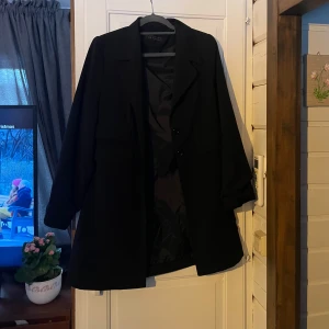 Svart kappa från Jacqueline de Young - Säljer en stilren svart kappa från Jacqueline de Young i storlek M. Kappan har en snygg passform och vaddar i axlarna och knappar framtill!! Nästintill nyskick!