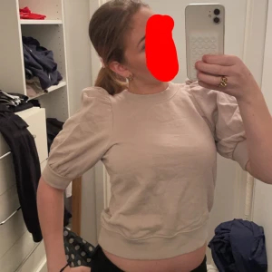 Beige kortärmad topp med puffärmar - Säljer en superfin beige topp med puffiga kortärmar. Den är perfekt för både vardag och fest! Toppen är i ett mjukt material och har en bekväm passform. Passar perfekt till jeans eller kjol. 🥰