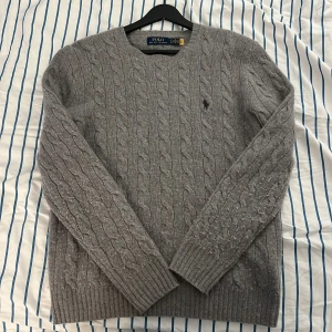 Grå stickad tröja från Polo Ralph Lauren - snygg grå stickad tröja från Polo Ralph Lauren med flätmönster. Perfekt för kyliga dagar. Tröjan är i mycket bra skick och supermjuk! Skriv efter minsta fråga! Pris kan förhandlas.