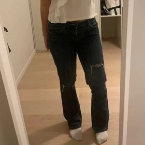 Mörkblå jeans med slitningar - Säljer ett par mörkblå jeans med coola slitningar på knäna. De har en klassisk femficksdesign och en bekväm passform. Om ni har frågor är det bara att skriva 🫶🏼 !inte mina bilder!