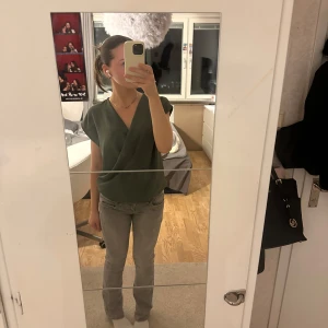 Mörkgrön omlottopp från Paul Smith - Snygg mörkgrön omlottopp från Zara i ett elegant och stilrent snitt. Toppen är ärmlös och har en djup v-ringning som ger en chic look. Perfekt för både vardag och festliga tillfällen. Passar bra till både jeans och kjol!