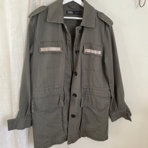 Jeansjacka mörkgrön - Militärfärgad jacka från Zara. Lång modell som slutar nedanför rumpan. Har fickor på båda sidor. Använt fåtal gånger. Ganska stor i storlek