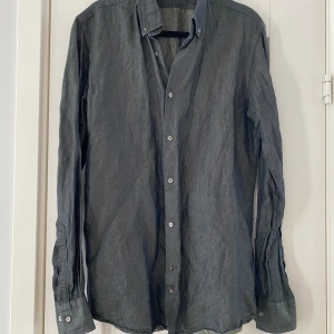 Mörkgrön halvlinne skjorta i strl 37 från J.Lindeberg - Mörkgrön halvlinne skjorta i strl 37 från J.Lindeberg.  Sparsamt använd och i fint begagnat skick.  Mått Över bröstet: ca 52 cm Längd från axeln och ner: ca 74 cm  56% linne och 34% bomull   Kommer från ett djur och rökfritt hem.