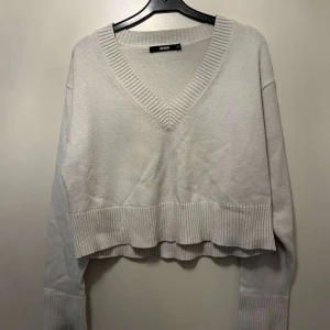 Beige croppad tröja från Bik Bok - Säljer en vit croppad tröja från Bik Bok. Tröjan har en v-ringad design och långa ärmar.  strl xs 